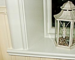 En bild på den vänstra sidan av en vit fönsterbänk. På fönsterbänken till höger står en vit lykta.