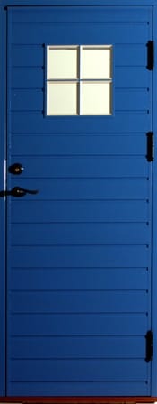 Blå ytterdörr i trä med horisontell panel och ett litet fyrdelat fönster upptill. Dörren har svart handtag, låsbeslag och gångjärn som kontrasterar mot den klara blå färgen.