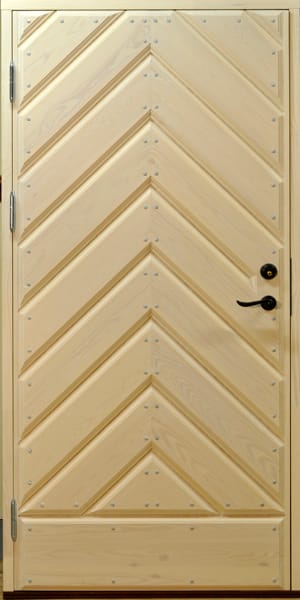 Ytterdörr i ljust trä med dekorativa snedställda paneler som möts i ett elegant fiskbensmönster. Panelerna är förstärkta med små metallnitar som ger en robust och gedigen känsla. Dörren har svart handtag och låscylinder placerade på höger sida, samt synliga gångjärn till vänster. Det ljusa träets naturliga ådring ger dörren en stilren och klassisk karaktär.