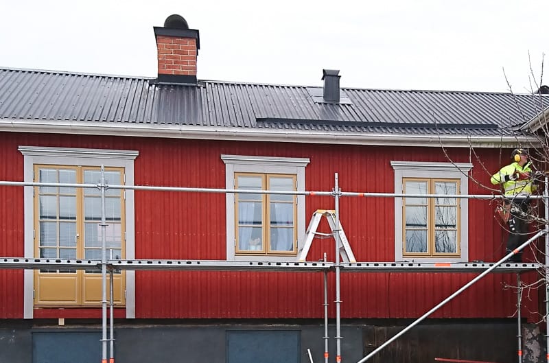 Fasad med spröjsade fönster och glasytor som släpper in ljus, med byggställning framför.
