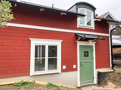Fasad med stort fönster och grön dörr; glasrutor ger tydligt ljusinsläpp och reflektioner i glaset.