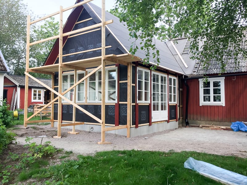Tillbyggnad med många fönster och glasad dörr, stora glasytor som släpper in dagsljus och ger tydlig spröjsindelning.