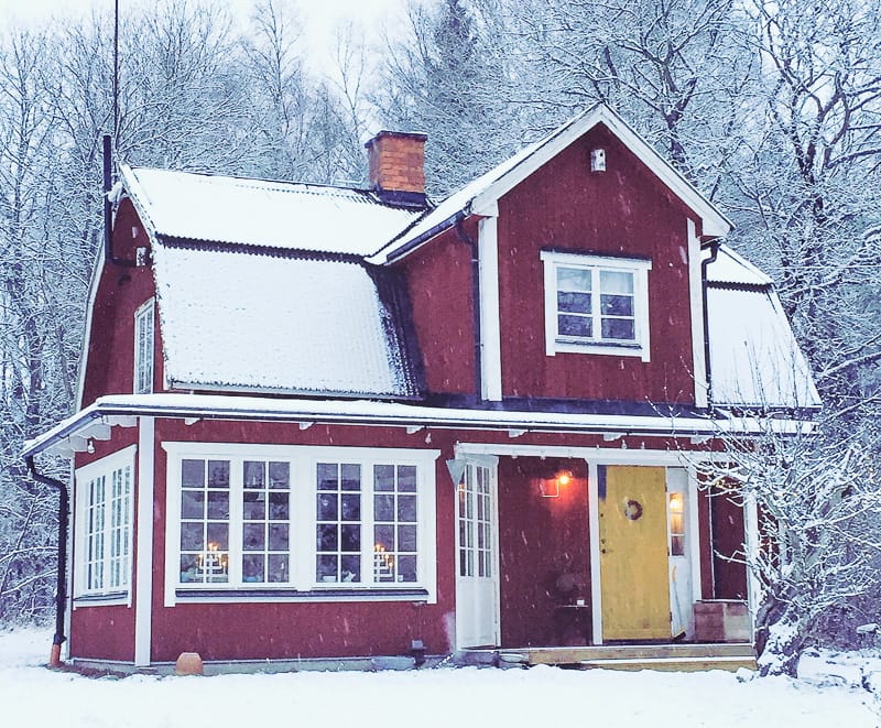 Husfasad med glasveranda där spröjsade fönster och glasade partier lyser varmt och visar tydliga glasrutor i flera fält.