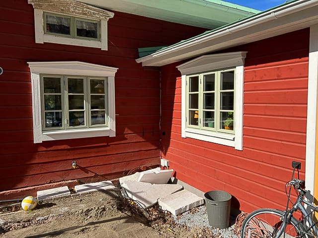Detalj av vitmålade fönster med spröjs och profilerade foder på röd träfasad